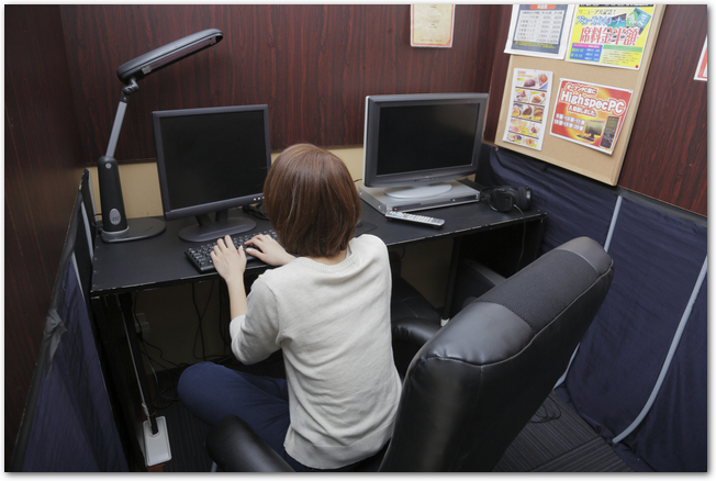 ネットカフェの個室でパソコンを操作する女性